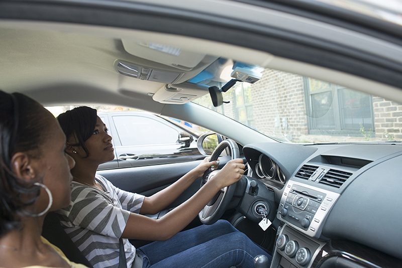 Two people are in a car, one is a passenger and the other is driving the vehicle.