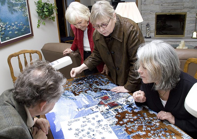 A photo shows four people working together to complete a puzzle.