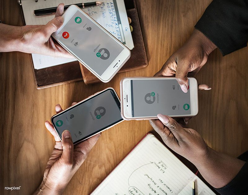 A close-up view of three people holding cell phones.