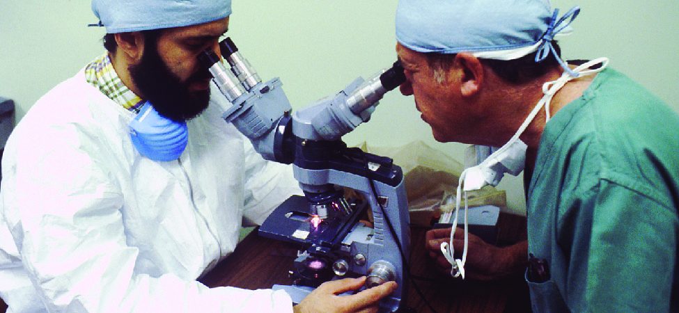 A photo of two scientists operating a microscope.