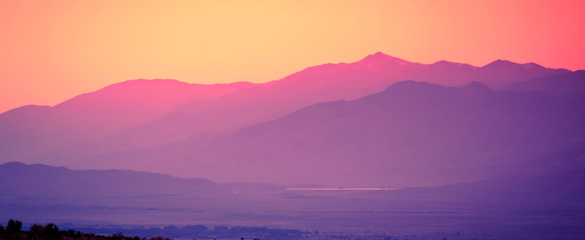 Landscape photograph of mountains with colors ranging from orange to pink to purple