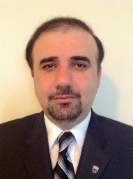 Portrait photograph of author Mohammad Mahbobi, wearing a dark suit and a striped tie.