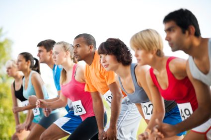 Photograph of a row of young runners crouched at the start line of a race, wearing numbered race bibs — illustration for the Statistical Literacy item on athletic admissions and SAT scores.