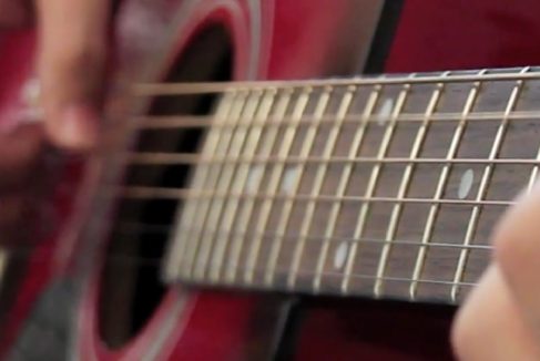 A photograph of a guitar being played.