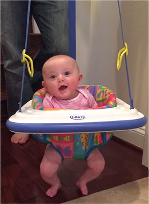 A photo of a baby in a hanging bouncer.