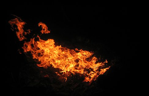 Vibrant orange and yellow flames dance against the dark night, creating a mesmerizing and intense glow.
