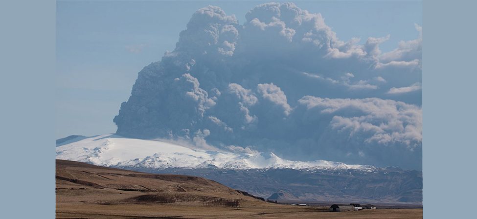 A photograph of an erupting volcano. A giant plume of gas and dust can be seen being ejected from it.