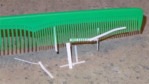 A photograph of thin strips of paper stuck to a plastic comb.